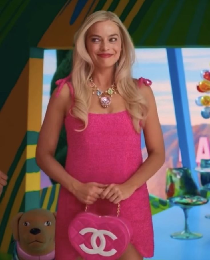 a woman in a pink dress holding a chanel bag