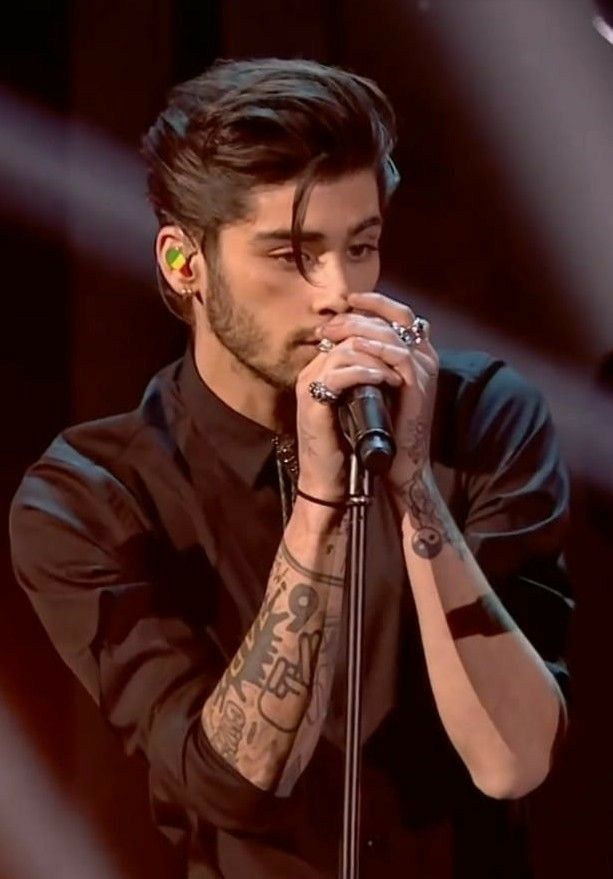 a man with tattoos on his arm holding a microphone