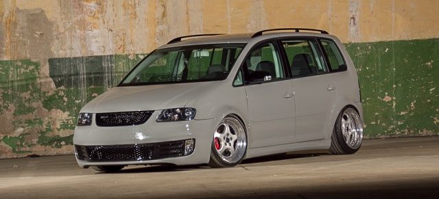 a grey van parked in front of a green wall