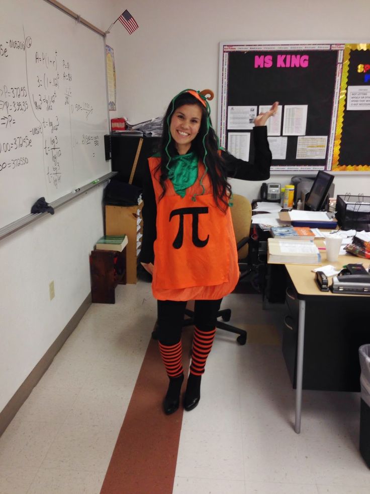 a woman dressed in an orange shirt and black tights standing in front of a whiteboard