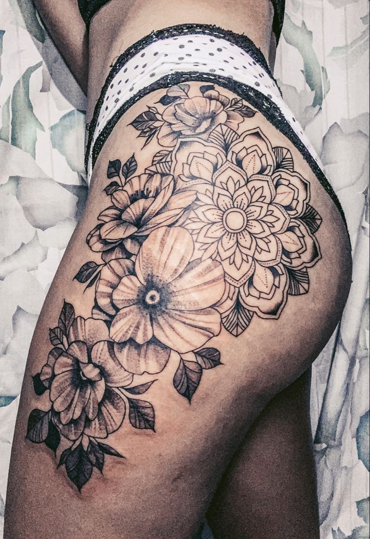 a close up of a woman's thigh with flowers on it and the bottom half of her leg