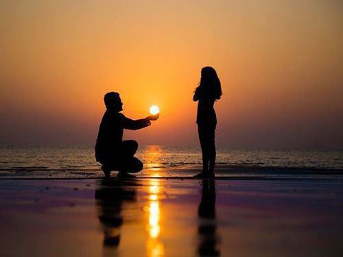 two people on the beach at sunset with one holding a frisbee in his hand