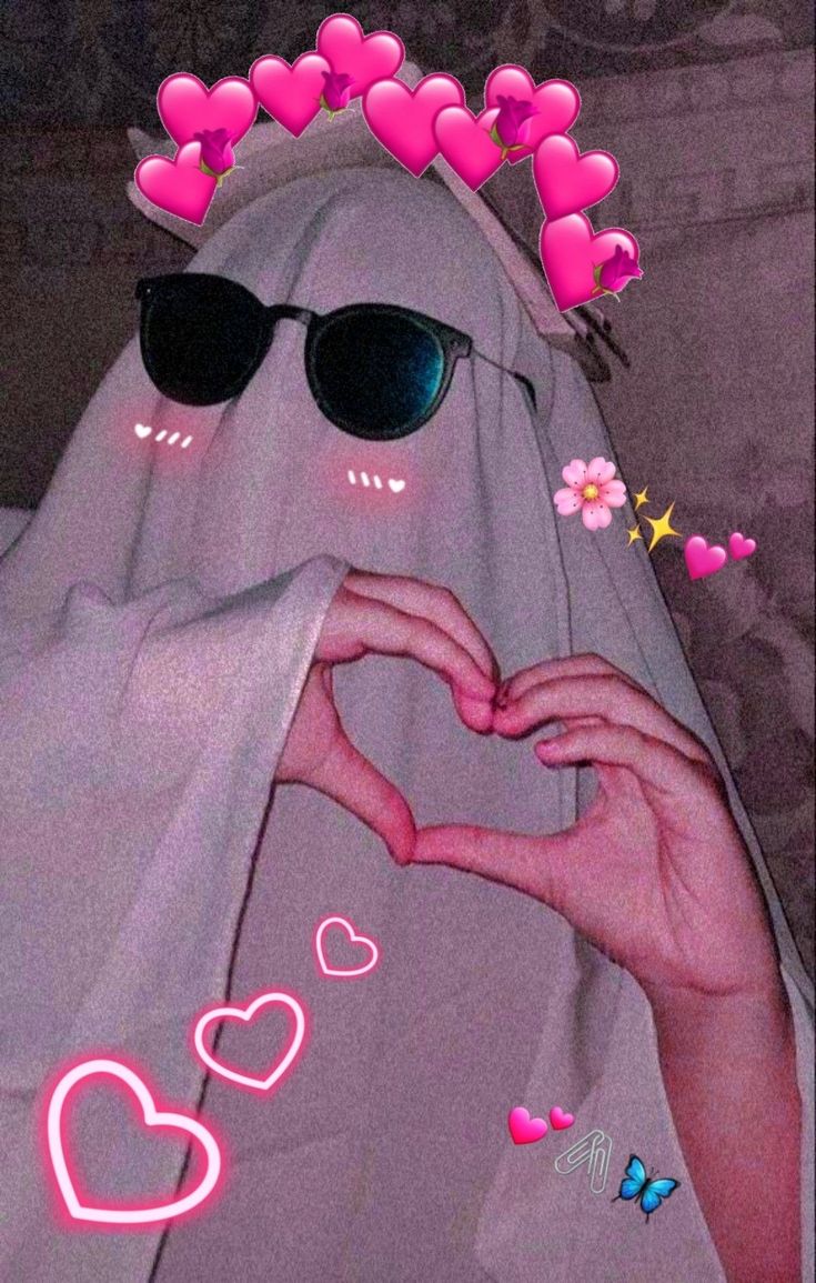 a person in sunglasses making a heart shape with their hands and wearing a white veil