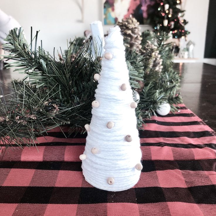 a white christmas tree sitting on top of a red and black checkered table cloth