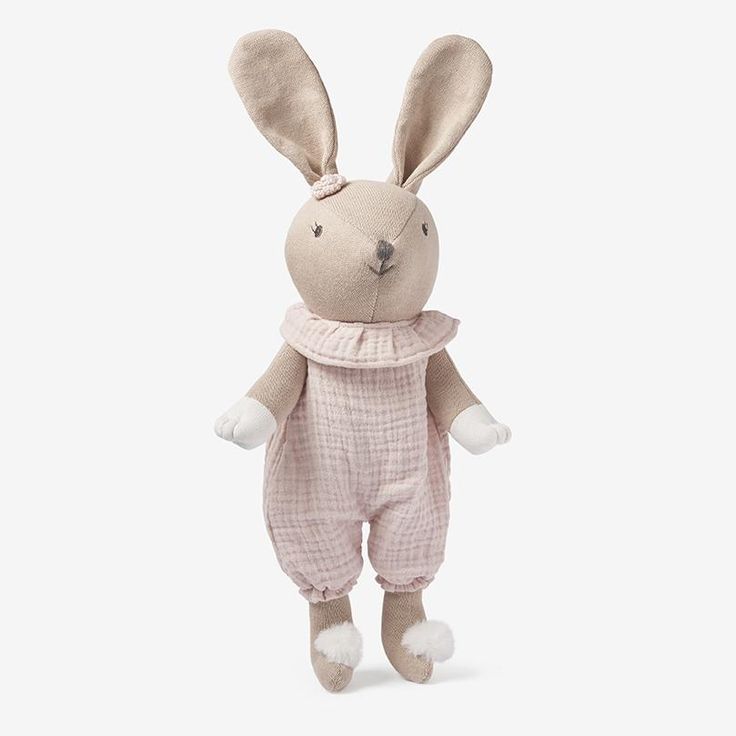 a stuffed animal rabbit wearing a pink outfit and scarf, standing upright in front of a white background