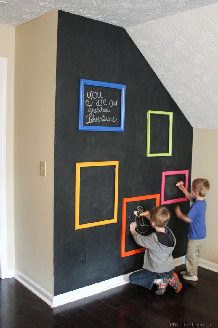 two young boys are playing with the chalkboard wall in their home, which is decorated with colorful squares and rectangles