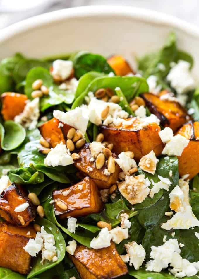 a white bowl filled with spinach and sweet potato salad