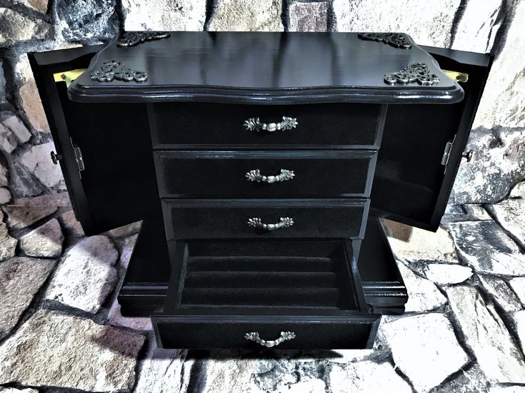 a black dresser sitting on top of a stone floor