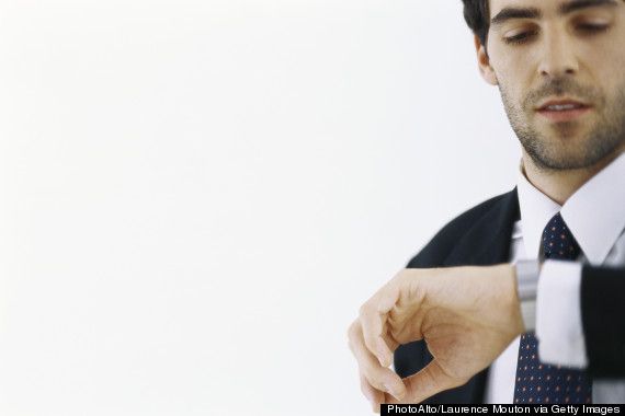 a man wearing a suit and tie is looking at his watch