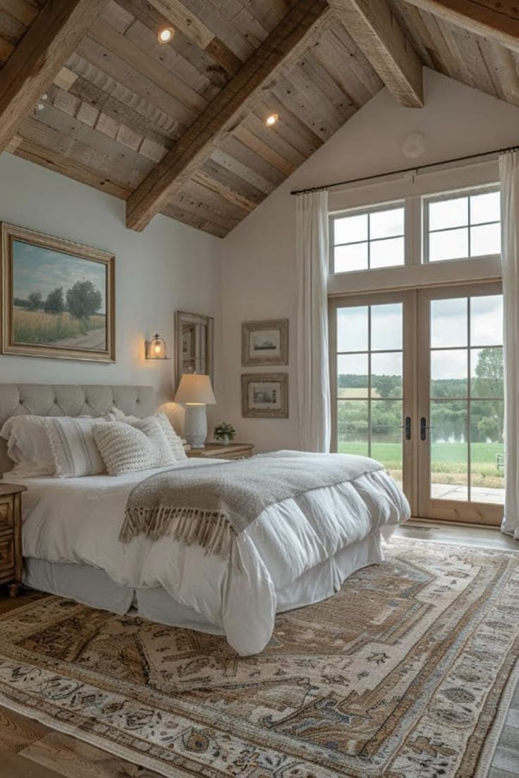 a large bed sitting under a wooden ceiling in a bedroom next to a window with french doors