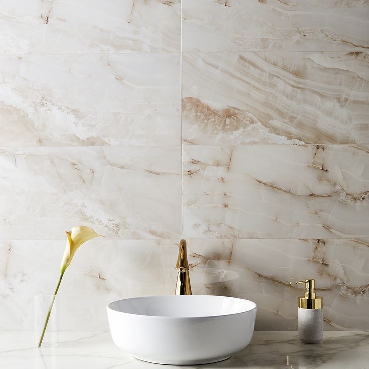 a white bowl sitting on top of a counter next to a vase with flowers in it