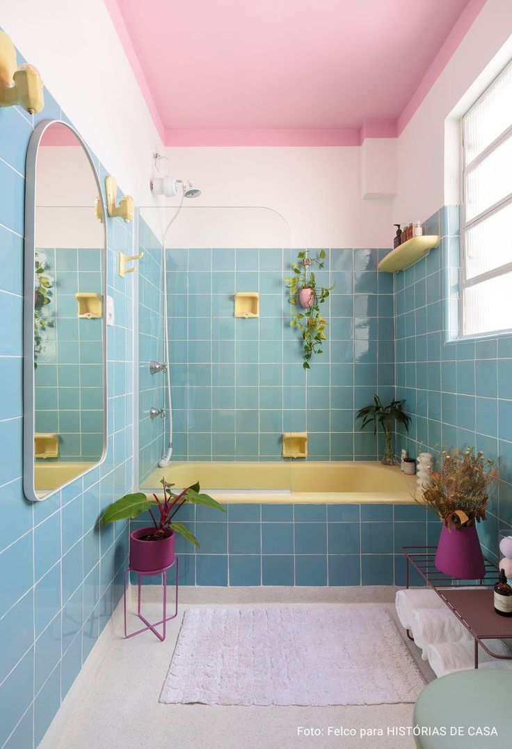 a bathroom with blue tiles and pink walls, including a bathtub in the center