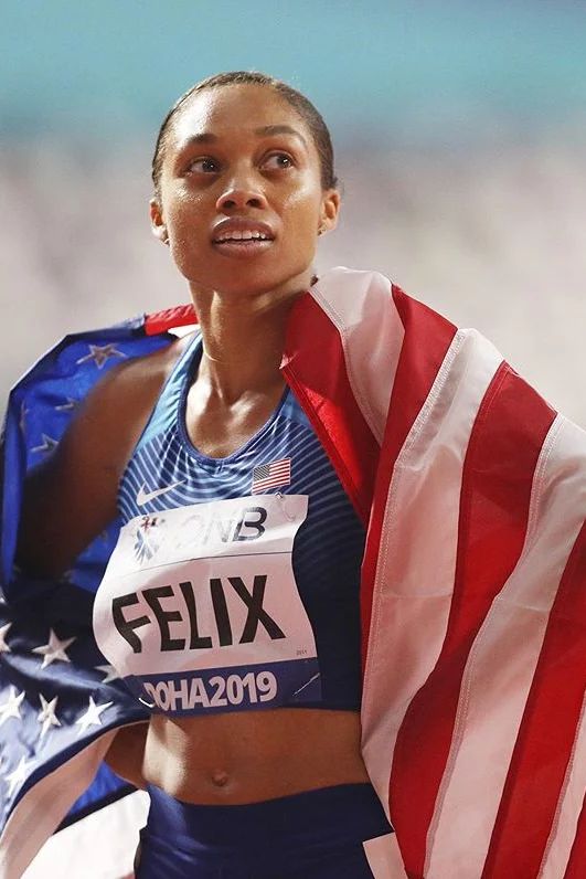 a female athlete with an american flag draped over her shoulder