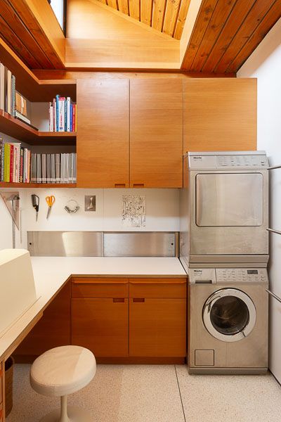 a washer and dryer in a small room with wooden cabinets on the walls