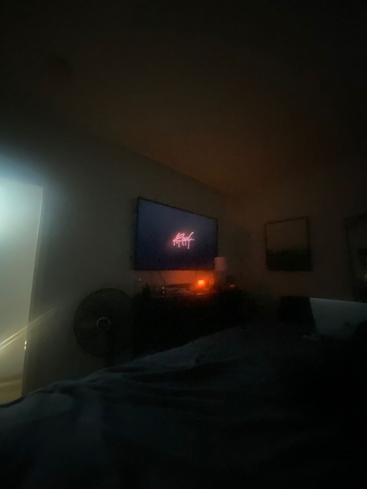 the television is on in the dark room with light coming from it's screen