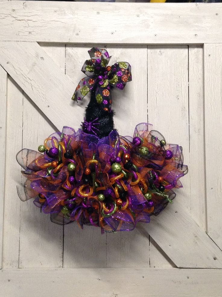 a purple and orange wreath hanging on the side of a white barn door with bells