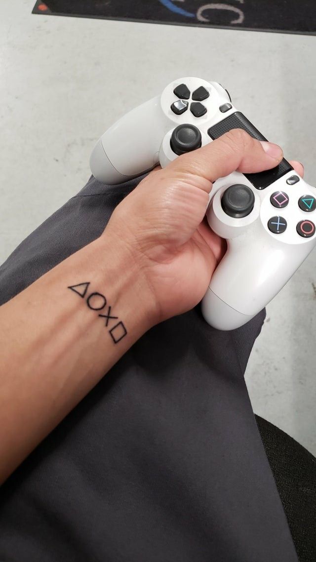 a person with a tattoo on their arm holding two video game remotes in their hands