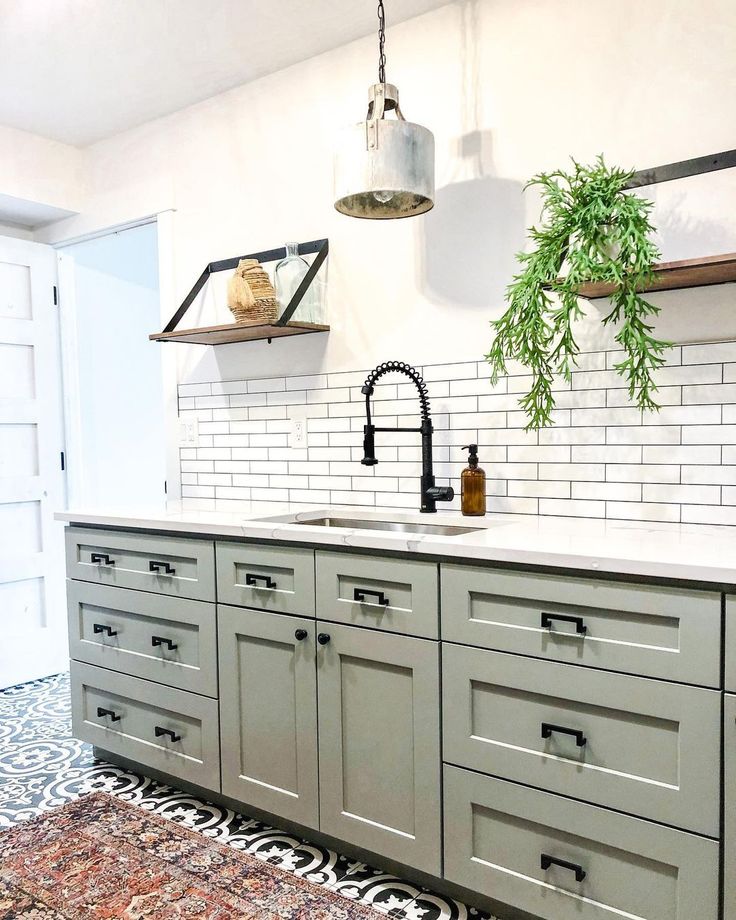 a kitchen with gray cabinets and white subway backsplash, hanging potted plant over the sink