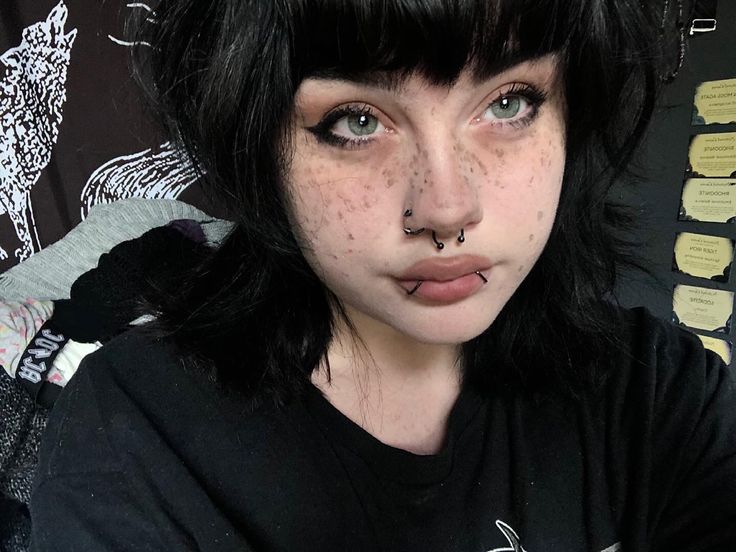 a girl with freckles on her face posing for the camera while wearing a black t - shirt