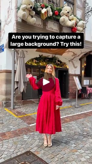 a woman standing in front of a building with teddy bears above her head and the caption are you trying to capture a large background? try this