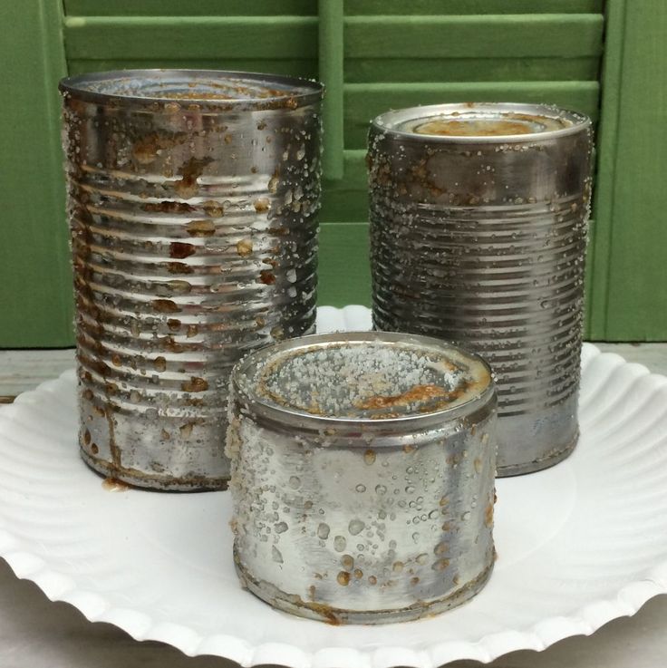 three tin canisters sitting on top of a white plate next to a green door