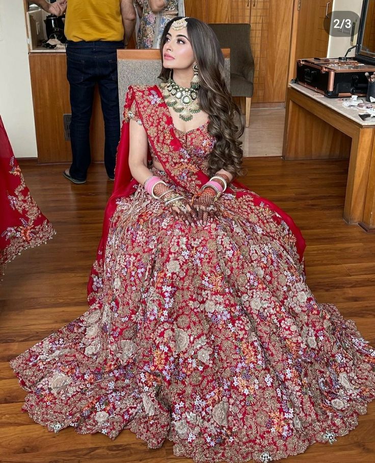 a woman in a red and gold dress sitting on the floor with her hands behind her head