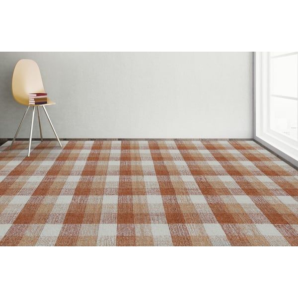 an orange and white checkered rug in the corner of a room with a chair