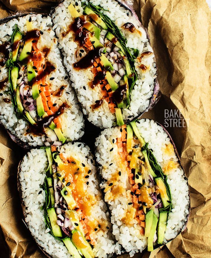 four sushi rolls with different toppings on top of brown paper