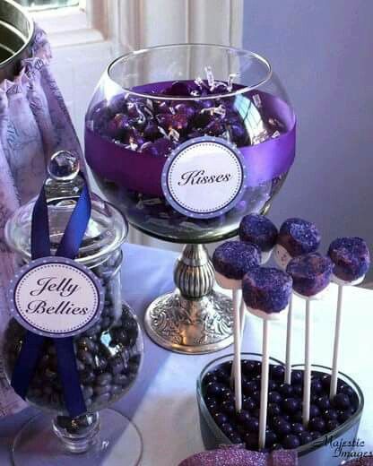 a table topped with lots of purple candies and lollipops on sticks