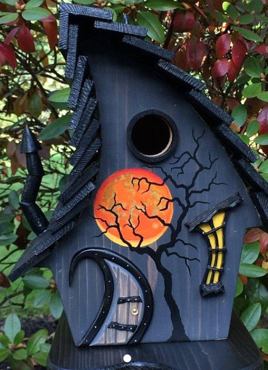 a black birdhouse with an orange moon on it