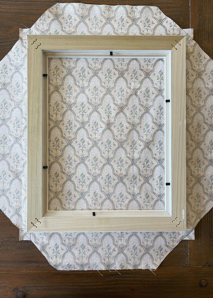 a wooden frame sitting on top of a table next to a wallpaper covered floor