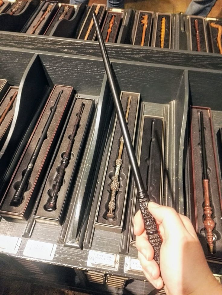 a person is holding a wand in front of many old drawers with other items on them