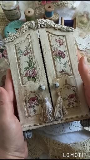 someone is holding an old wooden box with two doors and flowers painted on the sides