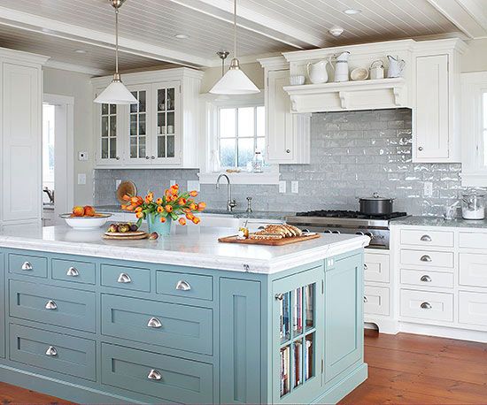 a kitchen with white cabinets and blue island