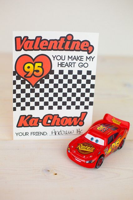 a red toy car sitting next to a valentine card