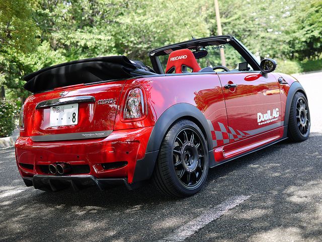 a red convertible car parked on the side of a road with its top down and it's hood up