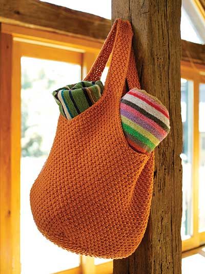 an orange purse hanging on a wooden pole with a striped ball in the bottom right corner