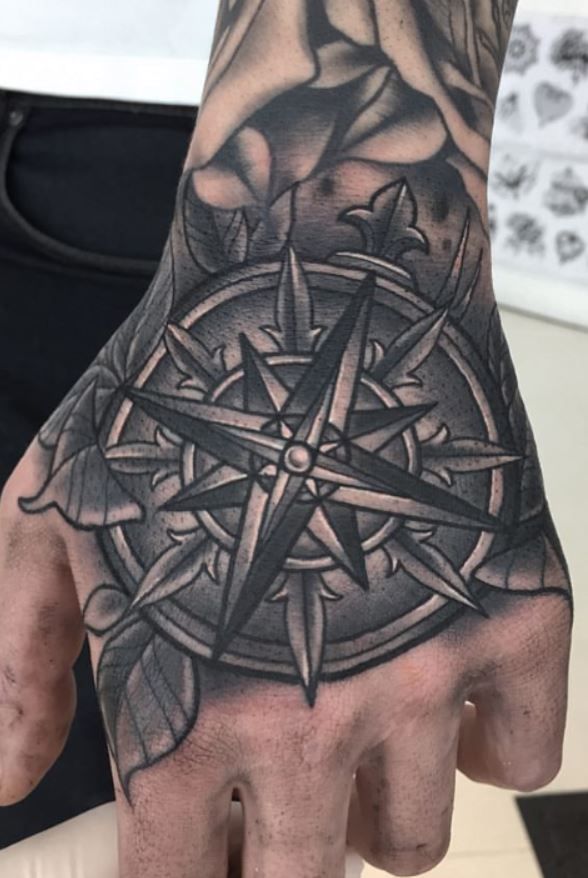 a man's hand with a tattoo on it and a compass in the middle