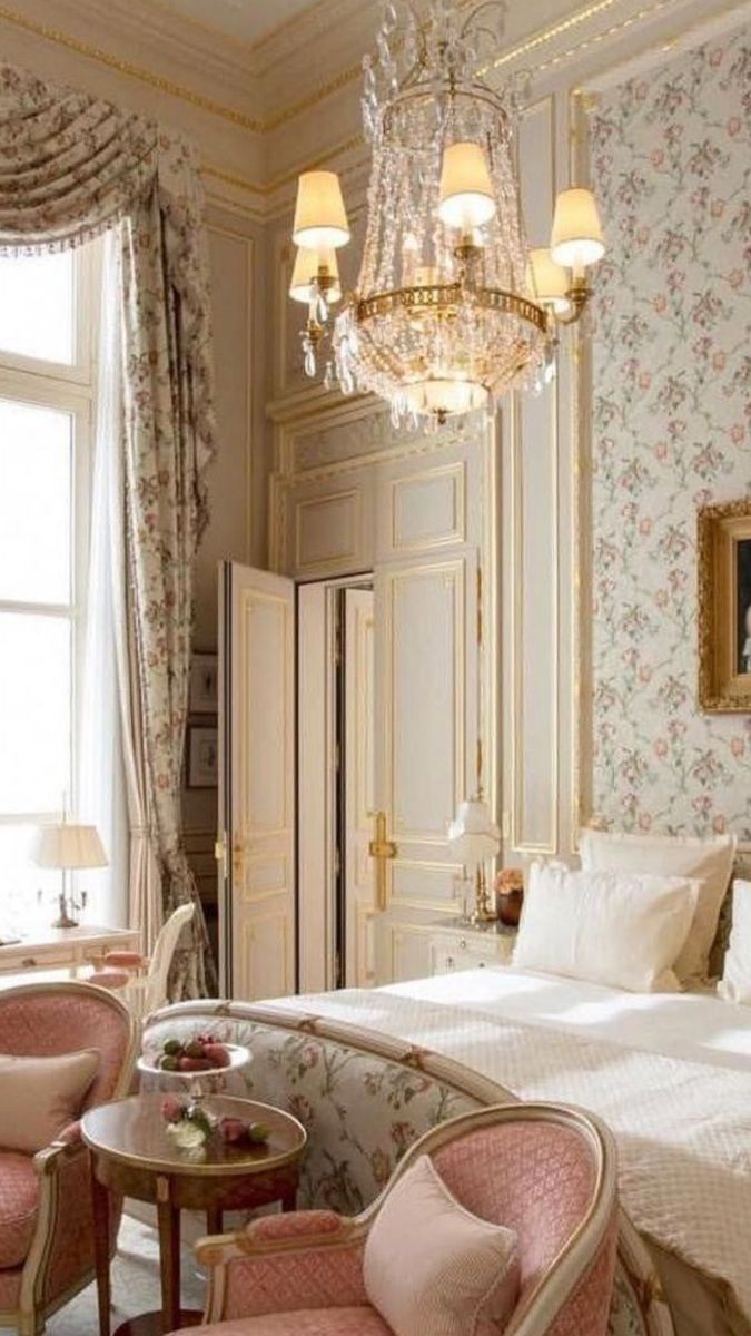 a bedroom with floral wallpaper and chandelier above the bed is decorated in pink