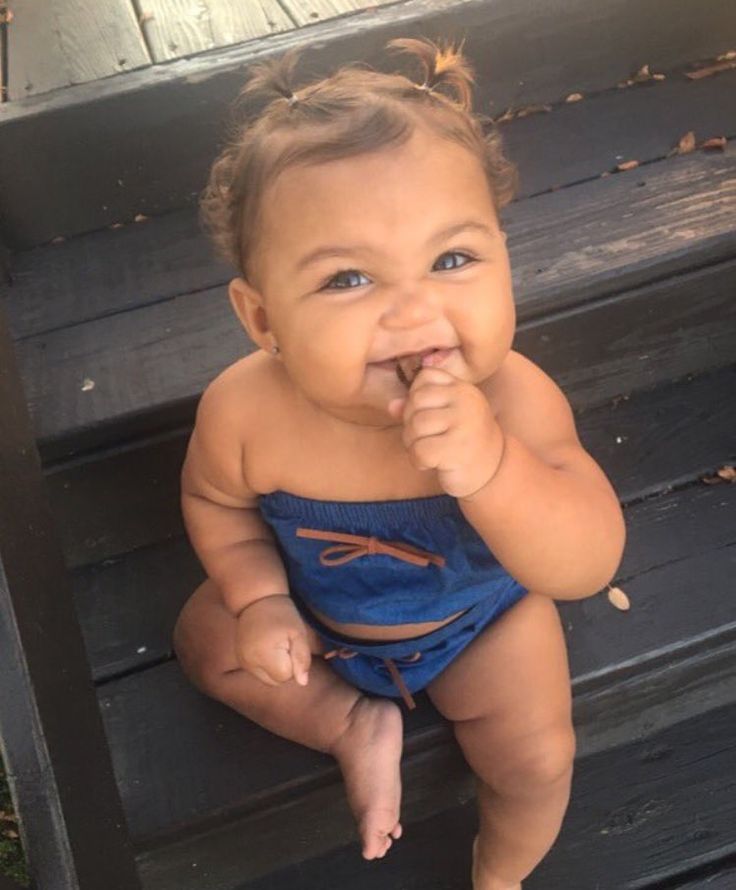 a baby sitting on top of a wooden bench next to an iphone screen with the caption's name