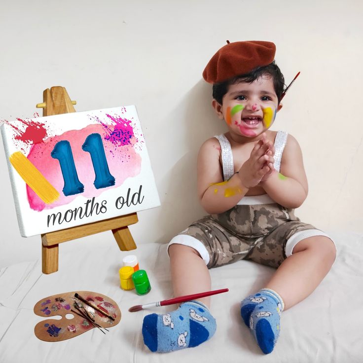 a little boy that is sitting on the ground with some paint in front of him