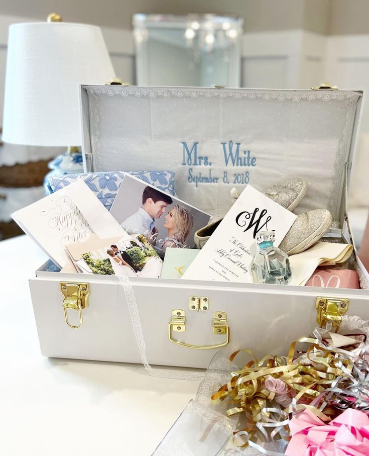 an open white suitcase filled with personal items on top of a table next to a lamp