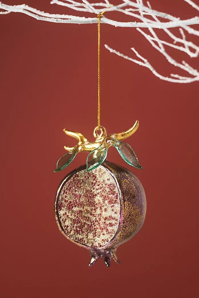 an ornament hanging from a tree branch with gold and red ornaments on it