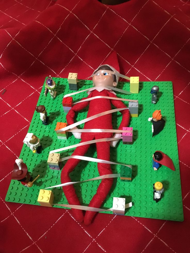 an elf laying on top of a green mat next to legos and other toys