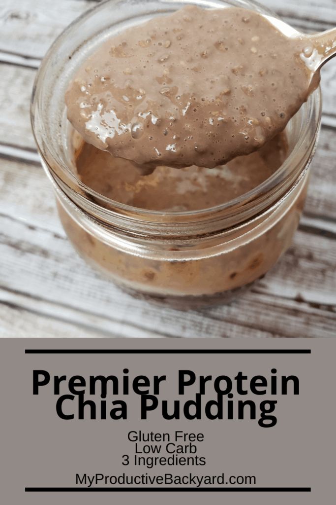 a glass jar filled with peanut butter on top of a wooden table next to a spoon