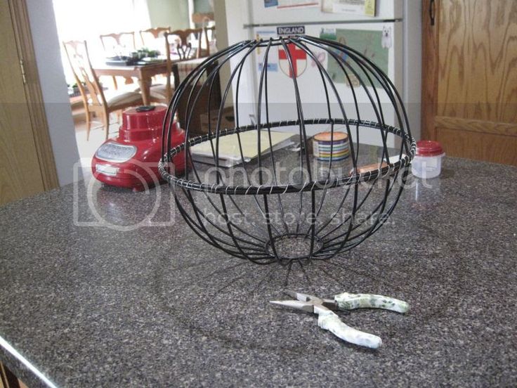 a kitchen counter with tools on it and a wire cage in the middle that holds scissors