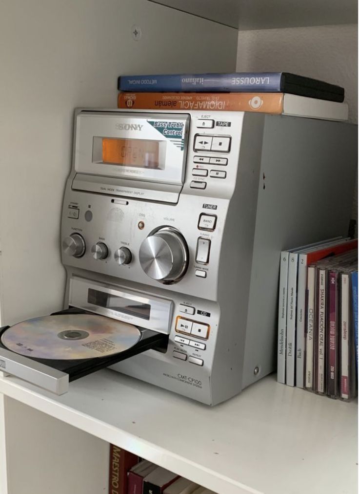 an old radio sitting on top of a book shelf next to a cd player and books