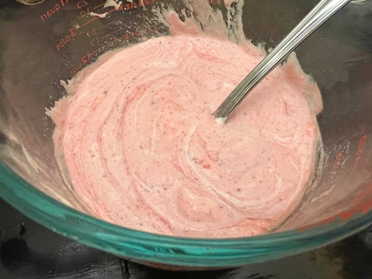 a mixing bowl filled with pink colored batter