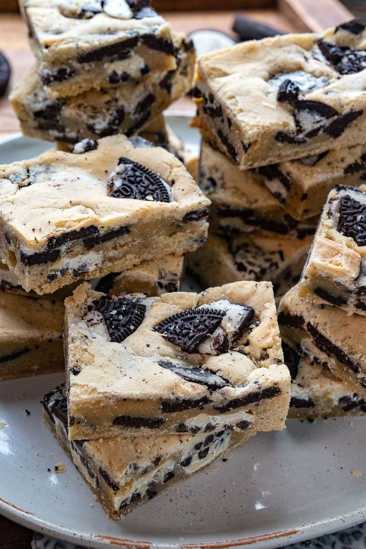 a white plate topped with cookies and oreo cookie dessert bars on top of a wooden table