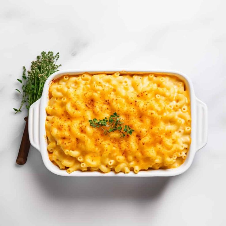 macaroni and cheese in a white casserole dish with parsley on the side